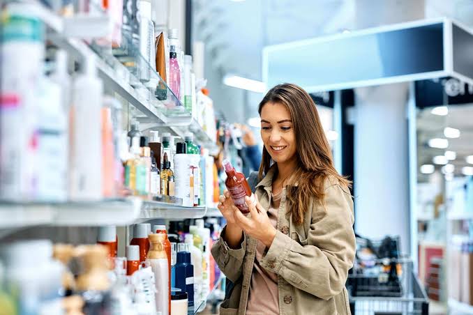 Woman choosing professional makeup and skincare products in a beauty store.