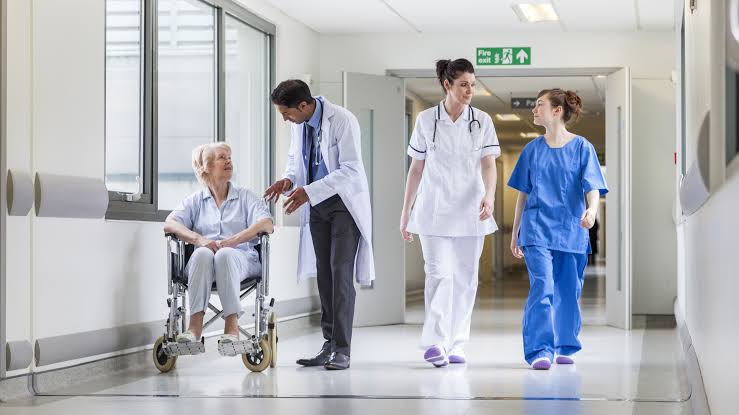 Doctor and nurses assisting an elderly patient in a hospital corridor during hospital services.