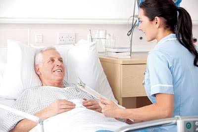 Nurse providing hospital services and patient care to an elderly man in a hospital room.
